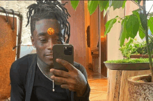 a man with dreadlocks is taking a selfie with his phone .