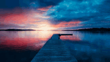 a sunset over a body of water with a wooden dock in the foreground