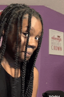 a girl with braids is standing in front of a purple wall with a sign that says " always invisible crown "