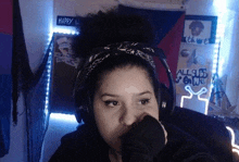 a woman wearing headphones and a bandana is sitting in front of a wall with graffiti on it .