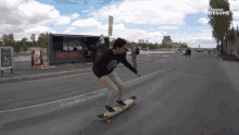 a man is riding a skateboard down a street in front of a food truck that says ' druckerei ' on it