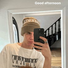 a man taking a picture of himself in a mirror with the words " good afternoon " above him