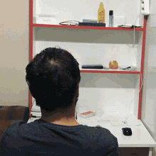 a man sits in front of a desk with a shelf that has a box that says power on it