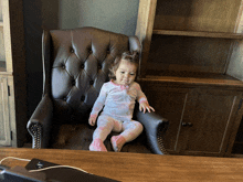 a little girl in pajamas sits in a chair with her mouth open