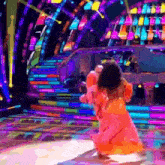 a girl in a pink dress is dancing on a stage with a piano in the background