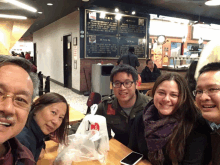 a group of people are posing for a picture in front of a sign that says ' chinese ' on it