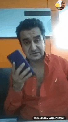 a man in a red shirt is holding a cell phone in front of a screen that says mobizen