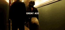 a man and a woman are walking down a hallway with the words `` great ass '' written on the bottom .