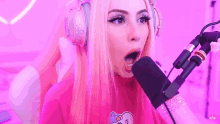 a woman wearing pink headphones and a pink shirt is talking into a microphone .