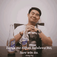 a man sitting at a table with two bottles of beer and a quote by along ang