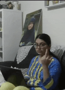 a woman is sitting on a couch using a laptop computer and making a funny face .