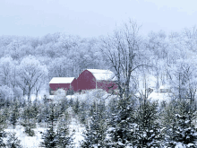 a snowy landscape with a red barn in the foreground