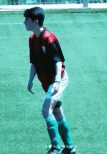 a soccer player wearing a red shirt and green shorts