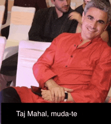 a man in a red shirt is sitting on a white chair .