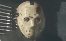 a person wearing a jason voorhees mask is looking at the camera .