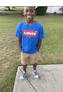 a young boy wearing a blue levi 's shirt and khaki shorts