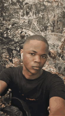 a young man wearing ear buds takes a selfie in a field