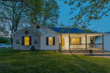 a white house with black shutters and a porch at dusk