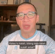 a man wearing glasses and a blue and white shirt is talking .