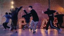 a group of young men are dancing in front of a brick wall and a sign that says " peace "