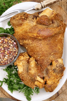 a white plate topped with a large piece of meat and a bowl of dipping sauce