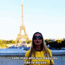 a woman standing in front of the eiffel tower with the words late mais alto que daqui eu não te escuto below her