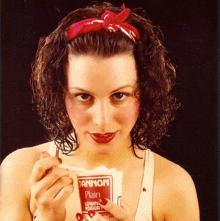 a woman is holding a carton of dannon plain yogurt