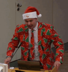 a man wearing a santa hat and a red jacket with christmas trees on it