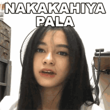 a woman with long black hair is standing in front of a fan with the words nakakahya pala written above her