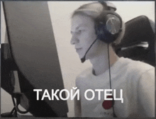 a man wearing headphones and a microphone is sitting in front of a computer screen that says takoi otel in white letters