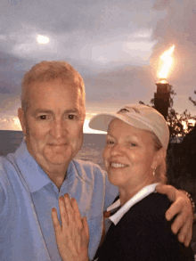 a man and woman are posing for a picture in front of a torch