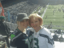 a woman wearing a seahawks jersey poses with another woman