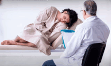 a man in a hospital gown sits on a bed with a doctor