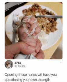 a person is holding rice in their fist in front of a plate of food with a fork .