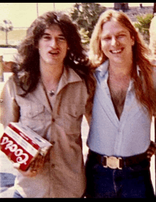 two men are posing for a picture and one is holding a can of coors