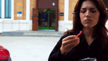 a woman eating a candy bar in front of a building with a sign that says ' a ' on it