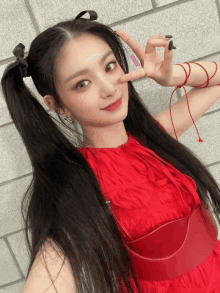 a woman wearing a red dress and pigtails makes a peace sign