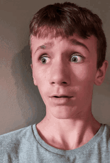 a boy with a surprised look on his face is wearing a grey shirt