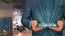 a man in a suit is holding a tablet with a glowing screen