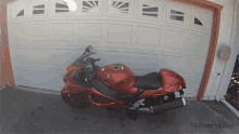 a red motorcycle is parked in front of a garage door that says motorcyclist on the bottom