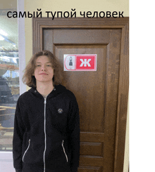 a young man stands in front of a wooden door with a sign on it that says жk