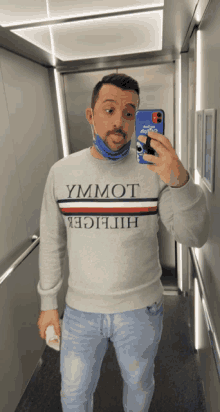 a man taking a selfie in an elevator wearing a tommy hilfiger sweatshirt