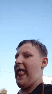 a young boy making a funny face with his tongue sticking out