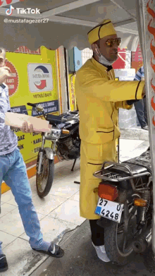 a man in a yellow coat stands next to a motorcycle with a license plate that says 27 u 4 248