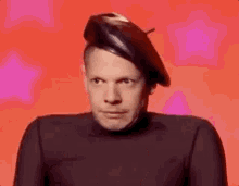 a man wearing a black beret and a black turtleneck is making a funny face .