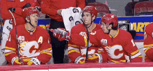 a group of hockey players are sitting on the bench and one has a bottle of water in his hand .