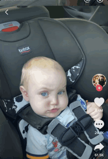 a baby sitting in a britax car seat making a face