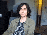 a young man in a striped shirt is sitting in a chair with the words watcher mode activated behind him