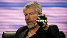 a man with a beard holds up a vinyl record