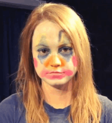 a woman with clown makeup on her face looks at the camera